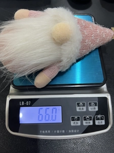 Pink knitted Christmas gnome plush doll on digital scale weighing 66 grams