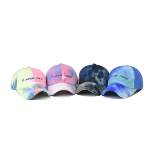 Macro detail of four tie-dye fleece baseball caps featuring if winter comes embroidery