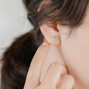 Close-up of a blue enamel whale stud earring in S925 sterling silver worn on an ear