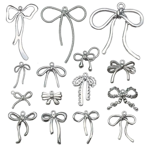Silver bow pendants collection for DIY jewelry making with metallic finish on white background