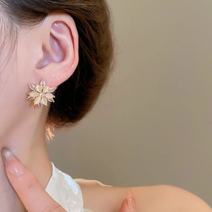 Detail of floral cat eye stone stud earring with zircon accents on a female model