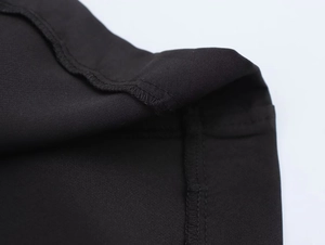 Close-up of high-quality overlock stitching and knit texture on black sleeveless dress