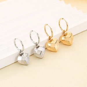 Detail of geometric heart earrings in gold and silver finish on white textured stand