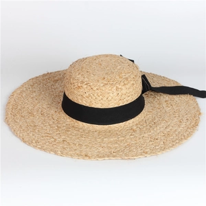 Close-up of wide brim raffia sun hat with elegant black ribbon bow decoration