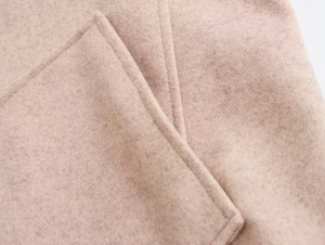 Makroaufnahme von hellbeige Wollmantelstoff mit feiner Textur und ordentlichen Nähten