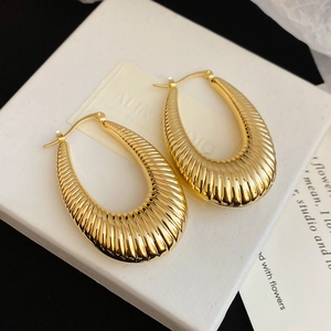 Detail of gold U-shaped hoop earrings with vertical texture on a white display box