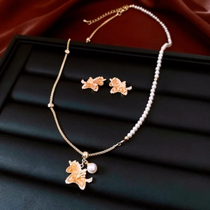 Detail of gold unicorn jewelry set with pearls and enamel on a dark background