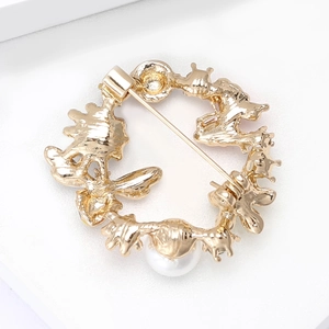 Close-up of golden wreath brooch with white pearl inlay and textured metal finish