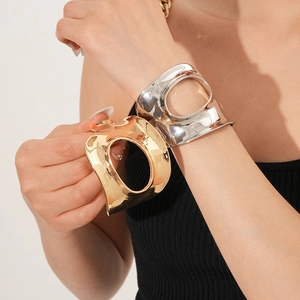 Détail de bracelets manchettes géométriques évidés en finition or et argent sur poignet