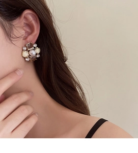 Close-up of vintage flower earrings with pearl and rhinestones on woman's ear