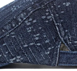 Detailed close-up of fine stitching and woven texture on navy denim newsboy cap