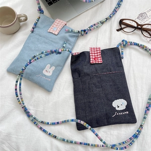 Close-up of cute embroidered denim mini bags with colorful beaded straps and plaid details