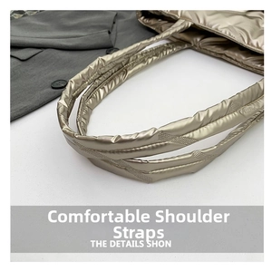 Detailed view of padded champagne gold quilted shoulder strap on a fashion tote bag
