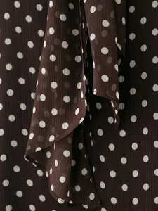 Primo piano di leggero tessuto popeline chiffon marrone scuro con motivo classico a pois bianchi