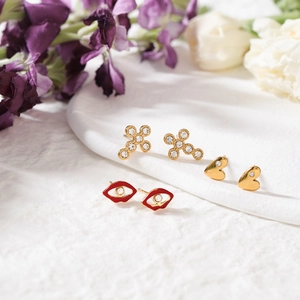 Trois paires de boucles d'oreilles en acier avec motifs de cœur, croix et lèvres