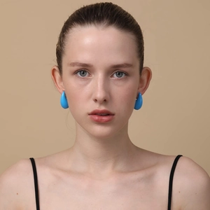 Close-up of blue teardrop earrings on a model showing polished finish and water drop shape