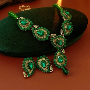 Detailansicht eines Vintage-Schmucksets mit smaragdgrüner Halskette und Ohrringen auf Samt