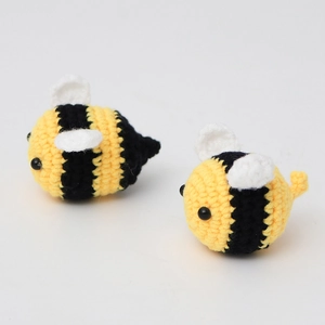 Nahaufnahme handgestrickter Bienenanhänger mit gelb-schwarzem Garn und weißen Flügeln