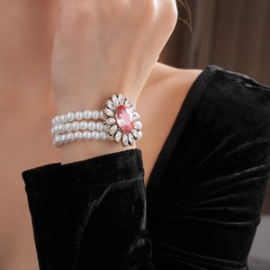 Détail d'un bracelet de perles à trois rangs avec fleur de cristal rose au poignet d'un mannequin