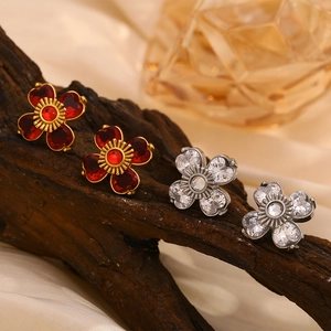 Détail macro de boucles d'oreilles fleur en or 18K et argent avec zircons rouges et blancs