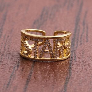 Golden adjustable STAR letter ring with cubic zirconia on a warm wooden surface