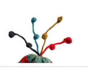 Detail of colorful knitted hat featuring woven tassels and vibrant yarn pom-poms