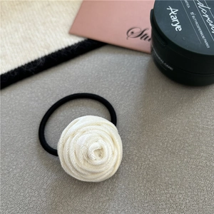 Close-up of a white velvet rose hair tie on a minimalist decorative stone surface