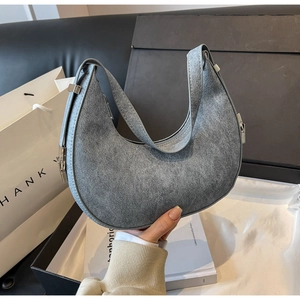 Detail showing grey crescent shoulder bag with vintage matte texture and silver buckle