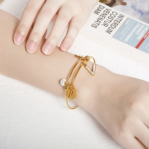 Adjustable gold titanium steel bracelet with V-shaped pendant and pearl on model wrist