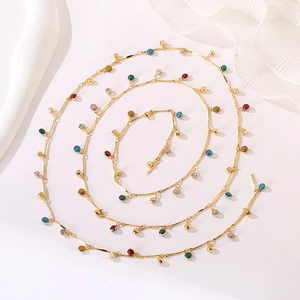 Detail view of a long gold chain necklace with colorful bohemian enamel bead charms