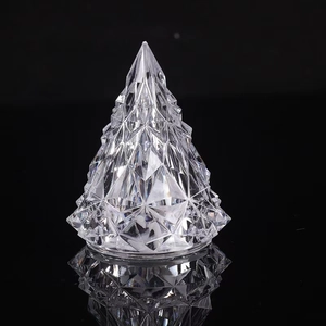 Macro shot of faceted crystal Christmas tree lamp reflecting on a black glossy surface