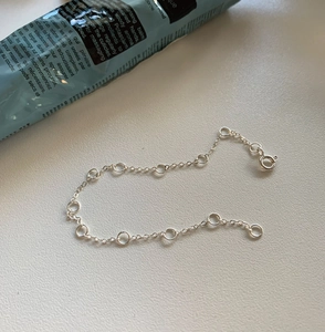 Macro detail of a S925 sterling silver knotted ring chain bracelet with spring clasp