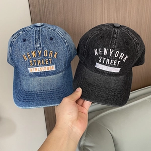 Detail shot of embroidered New York text on vintage washed denim baseball caps in blue and black