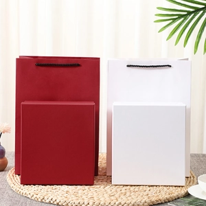 Detail view of red and white gift box sets with matching paper handles and woven mat