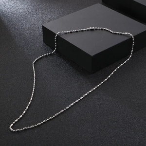 Detailed view of a silver stainless steel ball chain on a black minimalist background