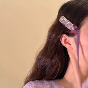 Purple butterfly hair clip with rhinestones and long tassels worn on a model's hair
