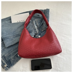 Close-up of a red woven leather tote bag with classic diamond weave on a white background