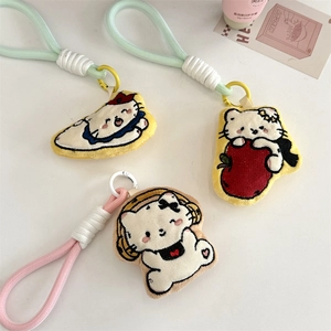 Detailed view of three white plush cat charms with colorful straps and cute embroidery