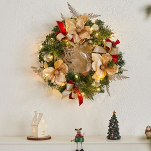 Illuminated Christmas wreath with gold flowers and LED lights on a white wall