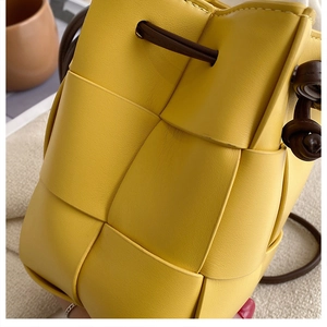 Close-up of yellow woven leather bucket bag with wide strips and drawstring closure