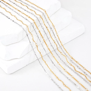 Polished gold and silver stainless steel stick chain necklaces on white stone display