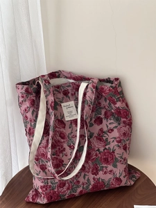 Détail d'un sac cabas en jacquard à roses rouges vintage avec anses crème sur tabouret