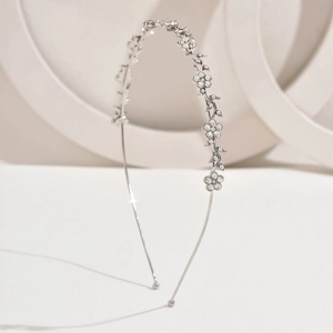 Detail view of silver metal headband with rhinestone flowers and leaf decorations