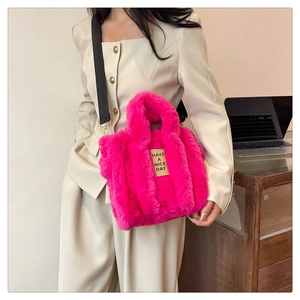 Detail of fuzzy pink plush tote bag with black strap and Have a Nice Day logo label