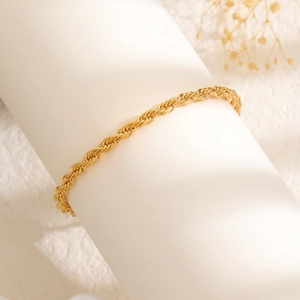 Detailed macro view of a golden twisted rope chain bracelet with intricate metallic texture