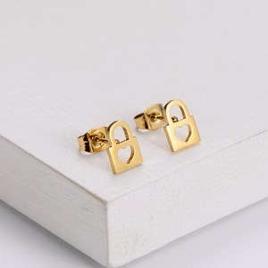 Macro view of gold-plated padlock earrings with hollow heart detail and polished finish