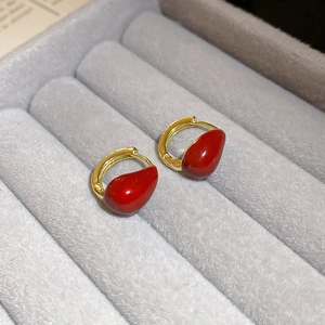 Close-up of red teardrop earrings with gold clasps on gray velvet jewelry display box
