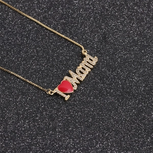Detail of gold Mama necklace with sparkling cubic zirconia and a small red heart charm