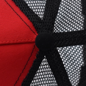 Detailed close-up of the red twill fabric and black mesh texture on the baseball cap top