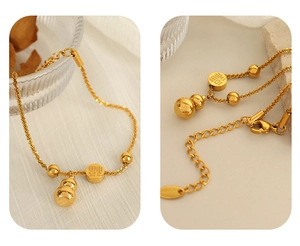 Detailed macro view of the gold-plated Fu character charm and gourd pendant bracelet